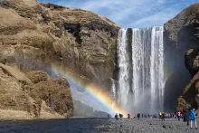 A group of people standing at the base of a waterfall.
